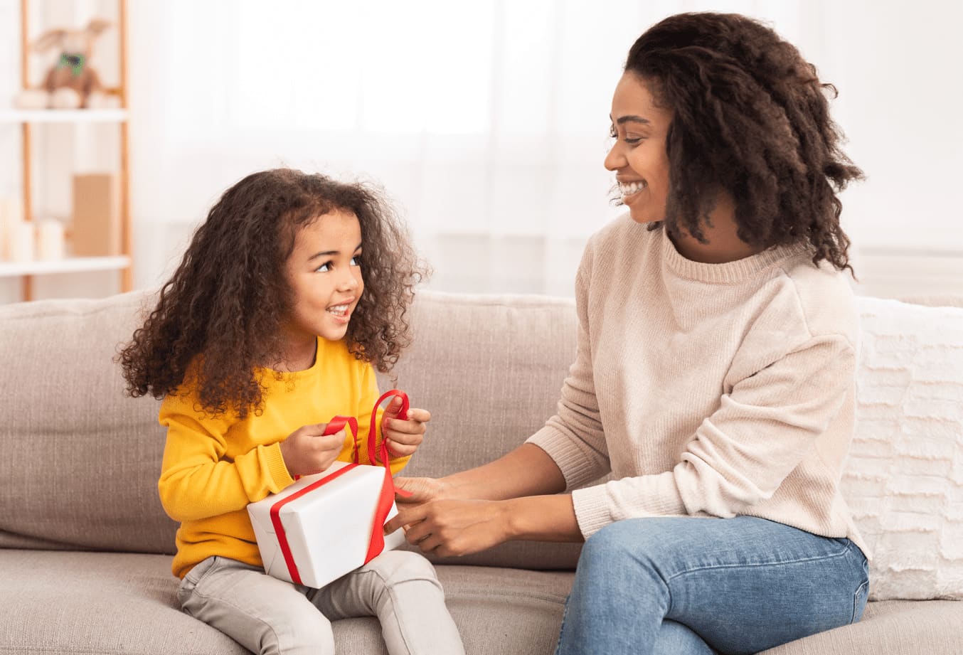 Imagem de mulher adulta entregando presente para criança.