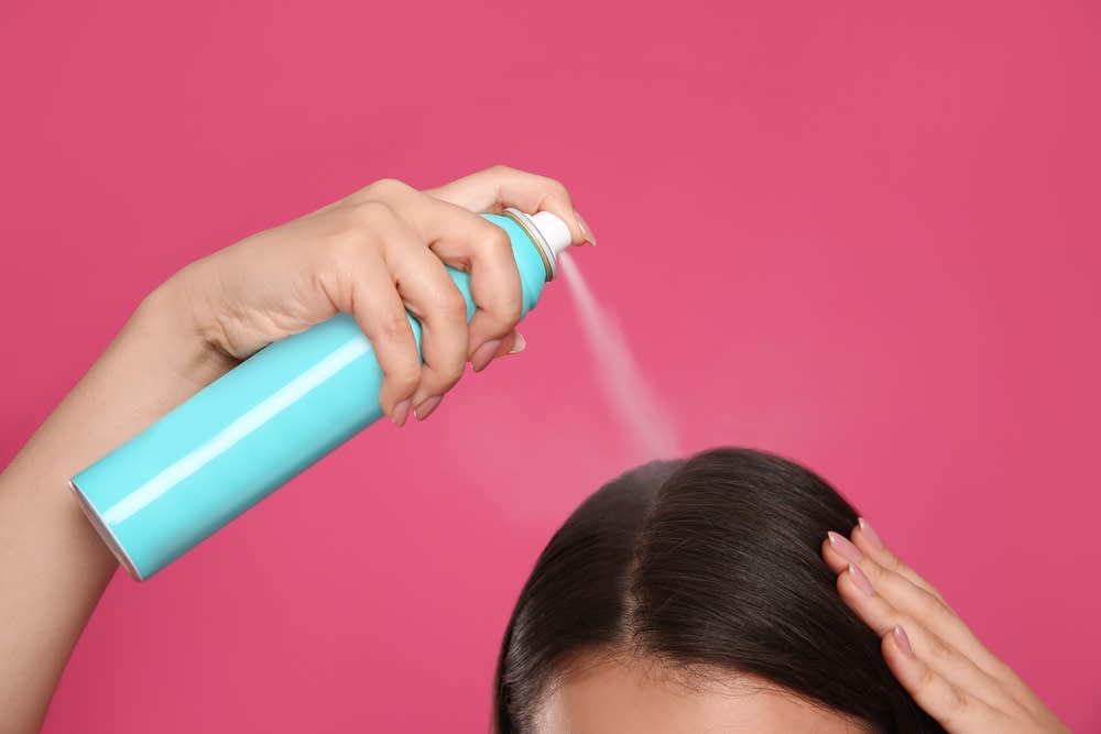 Imagem uma uma pessoa aplicando o spray com shampoo a seco no cabelo