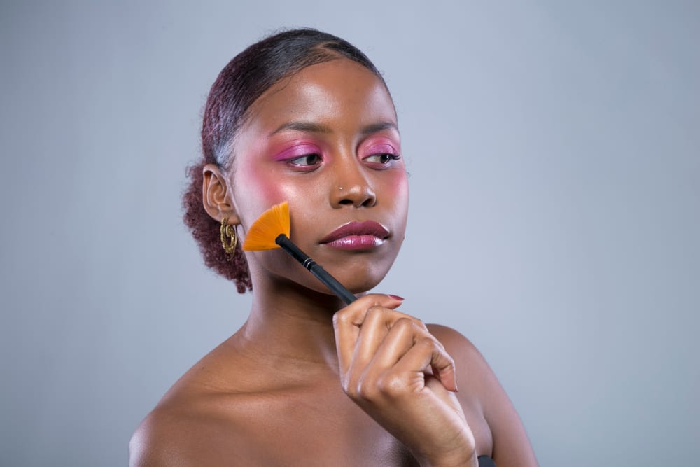 Imagem de mulher maquiada com predominância de cores magenta