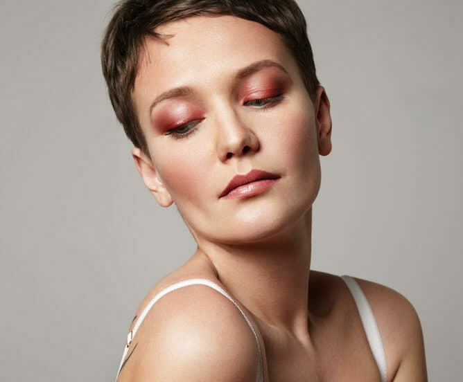 Mulher com maquiagem em tons rosados e avermelhados