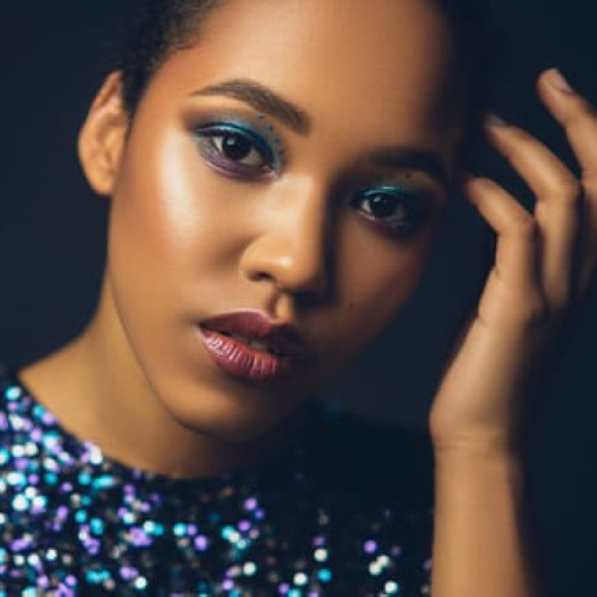 Mulher usando roupa de paetê e maquiagem colorida com acabamento metálico