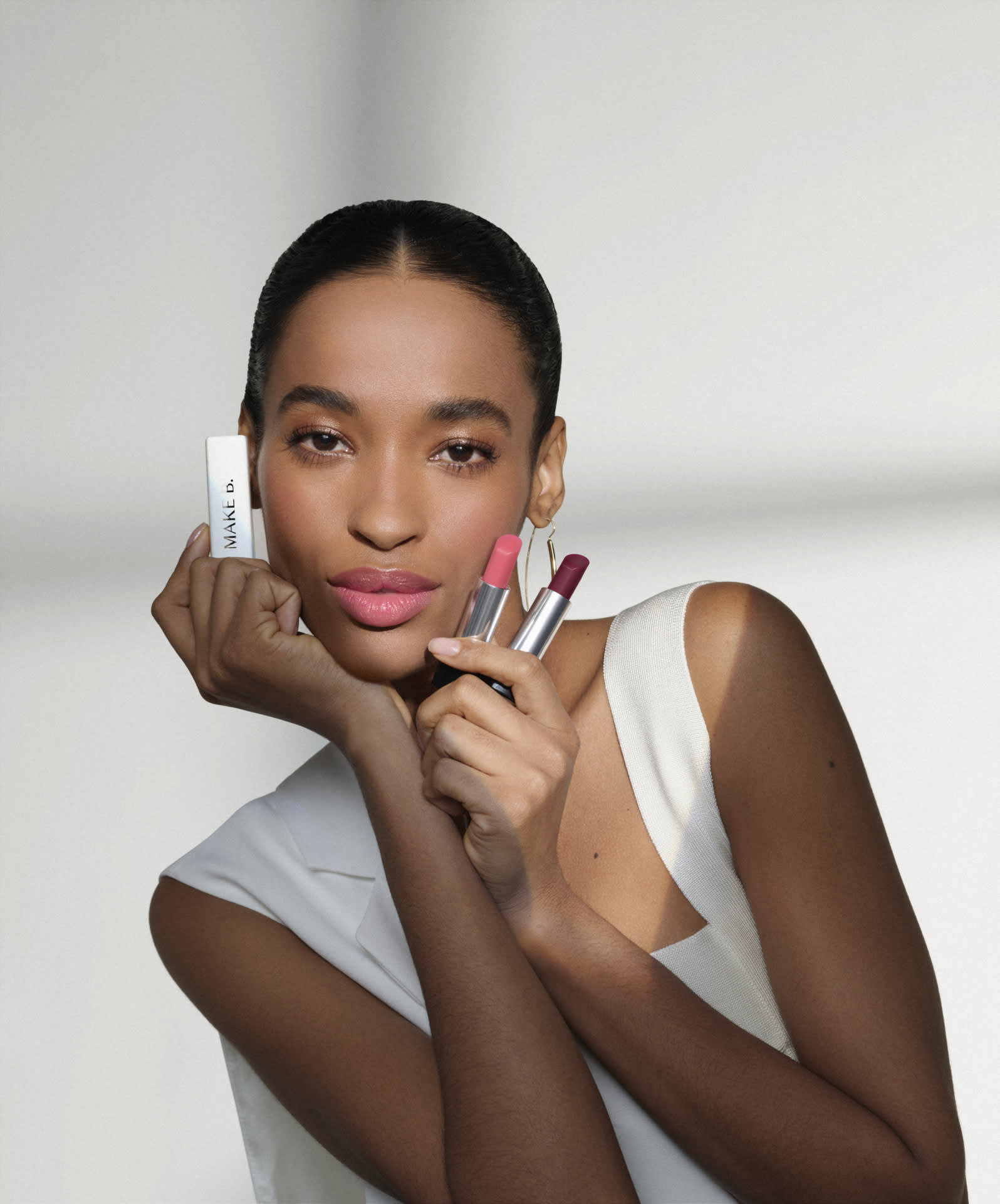 A imagem mostra uma mulher segurando os balms de Make B. próximo ao rosto, a foto dá destaque para o resultado nos seus lábios