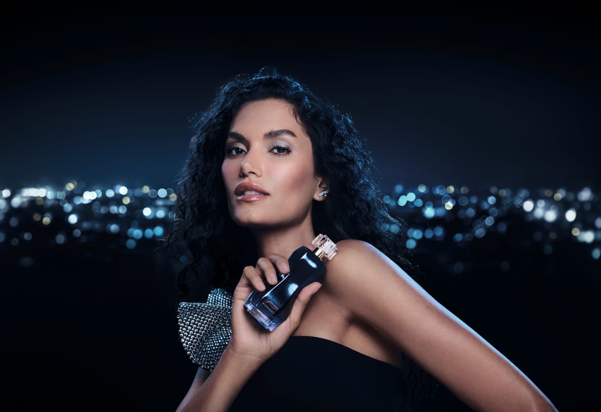 A imagem mostra uma mulher elegante segurando o frasco de Glamour Midnighr