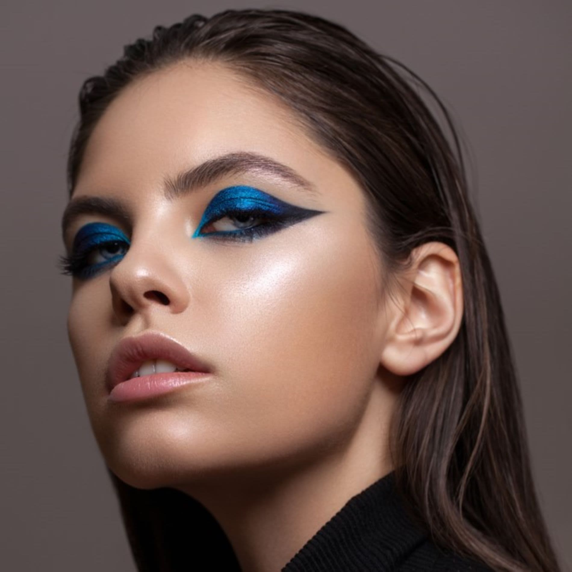 Mulher usando maquiagem azul nos olhos com desenho assimétrico