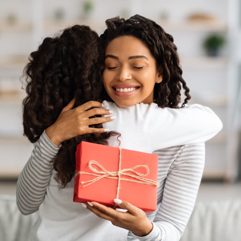 Mulher recebendo um presente e agradecendo com um abraço