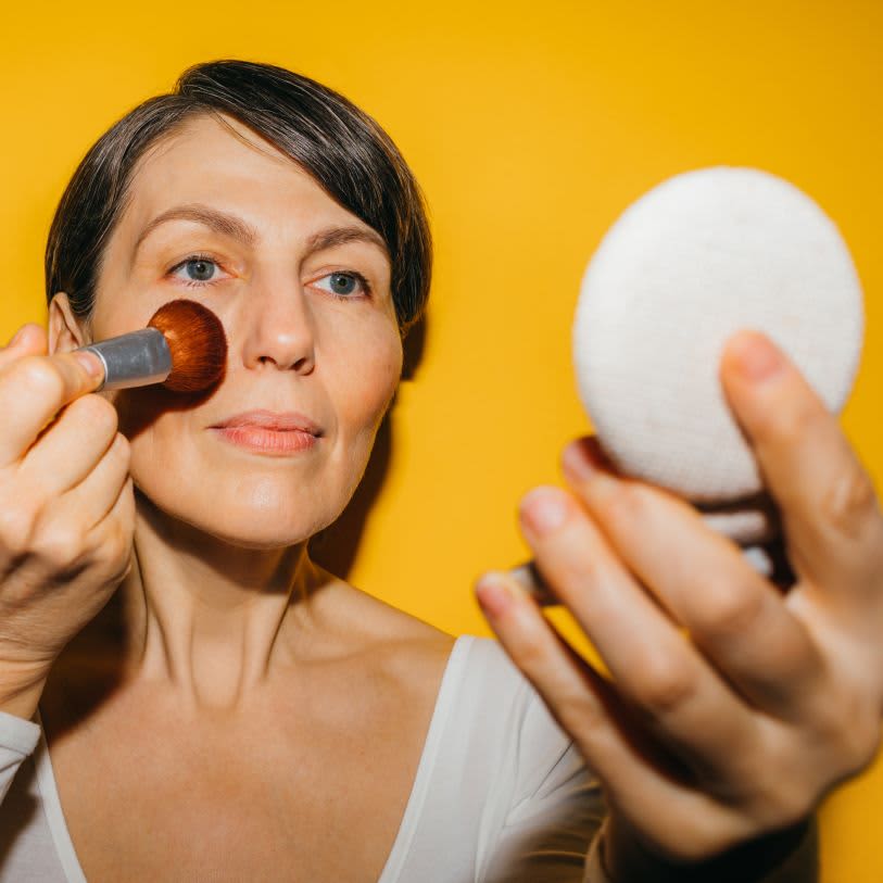 Mulher aplicando maquiagem em seu rosto