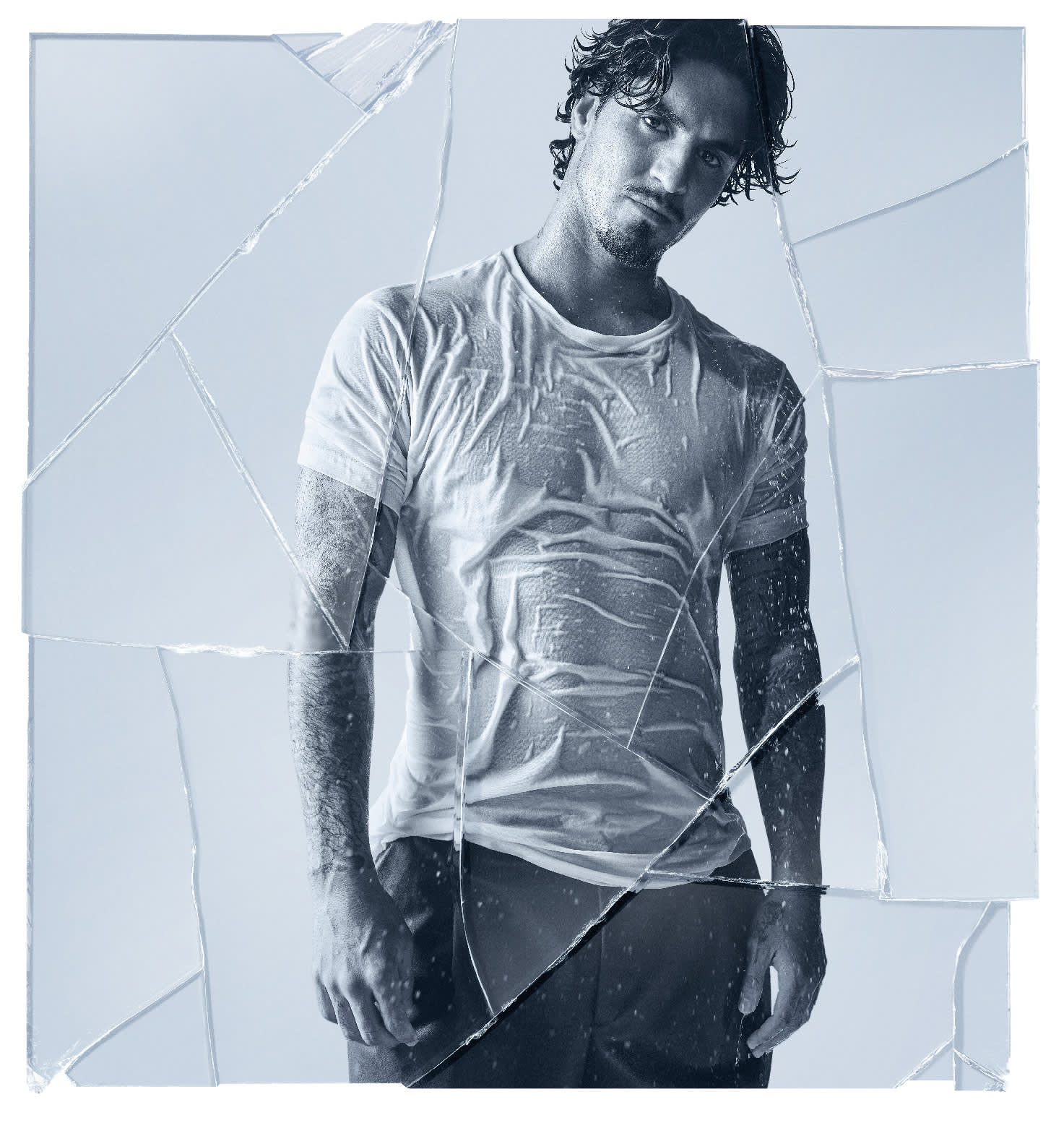 Gabriel Medina em um fundo claro, vestindo uma camiseta branca e molhada. Imagem com aspecto de vidro quebrado