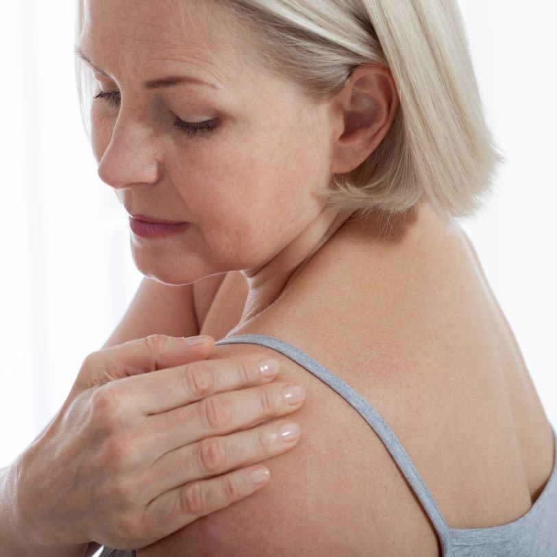 Mulher massageando seus próprios ombros com óleo de massagem