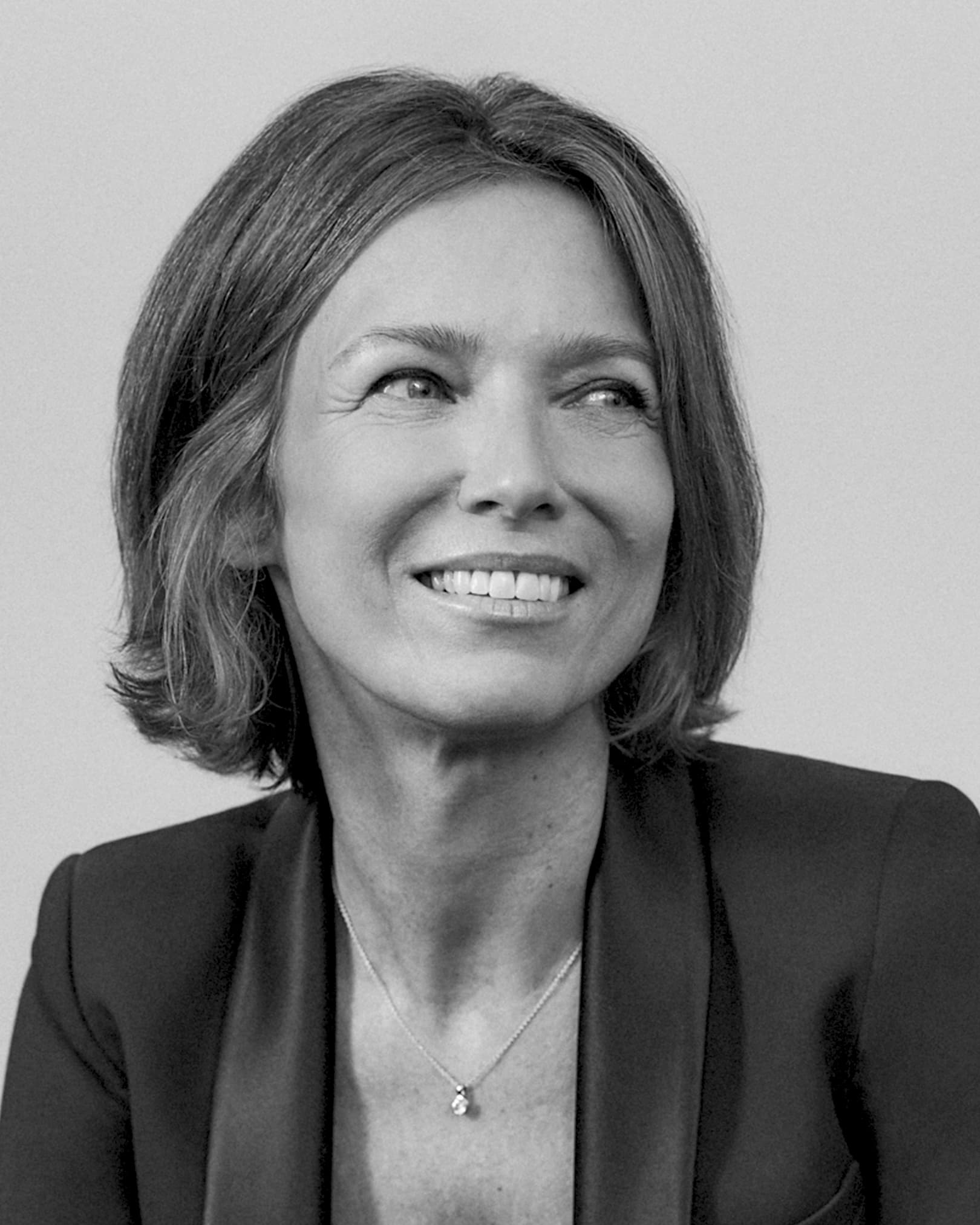 Foto em preto e branco da perfumista de Liz Emilie Coppermann. Ela tem cabelo liso, curto, está sorrindo e olhando para o lado.