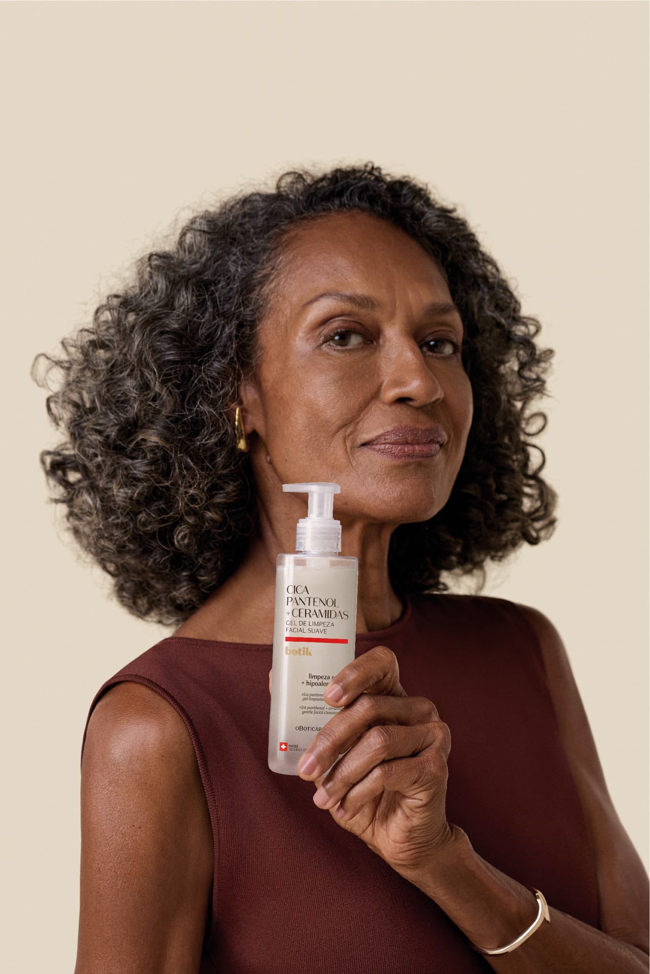 Mulher negra de pele madura segurando o gel de limpeza Botik.