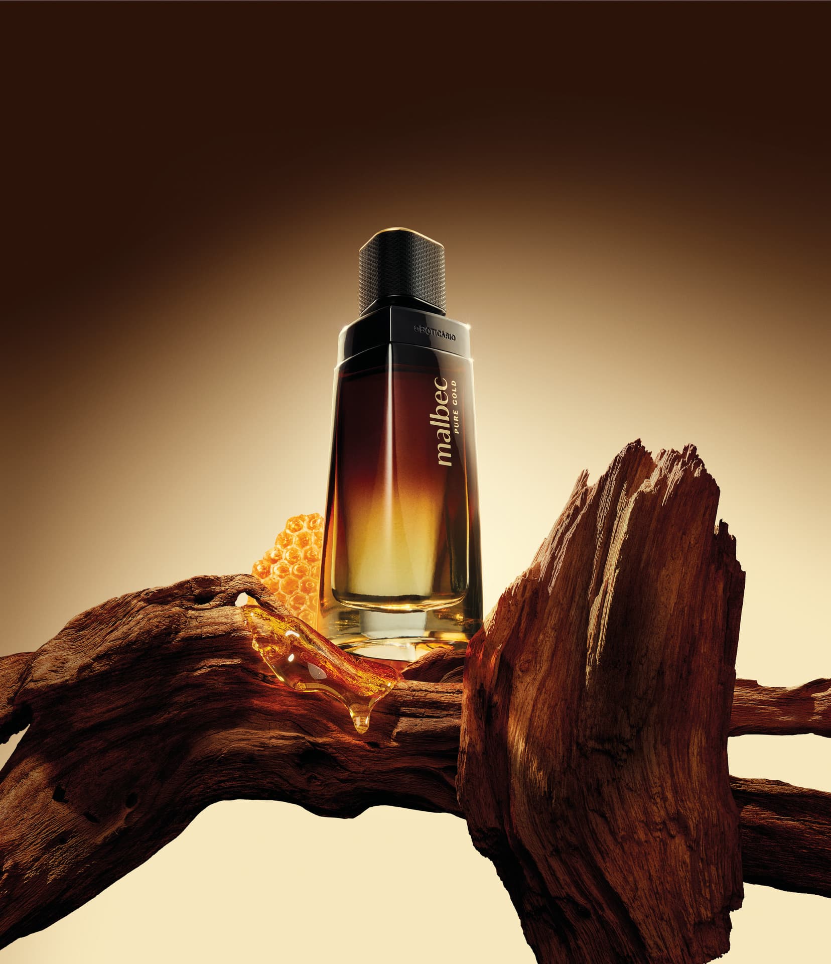 Frasco de Malbec Pure Gold sobre troncos de madeira e um favo de mel, com mel escorrendo.