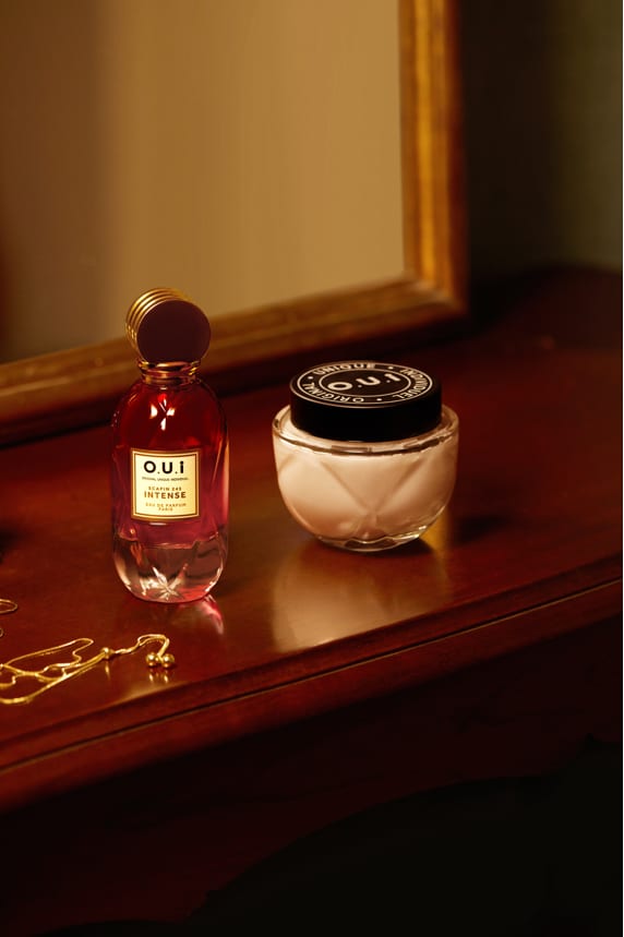 As imagens mostram os frascos do eau de parfum e do creme corporal em cima de uma mesa