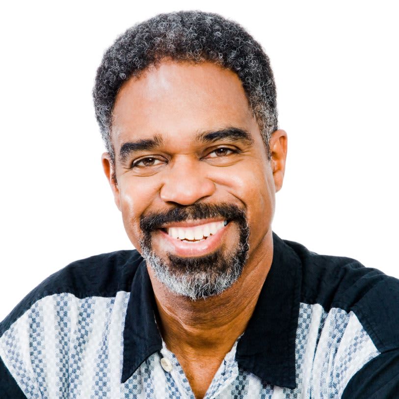 Homem de pele negra com barba e cabelos grilhados sorrindo