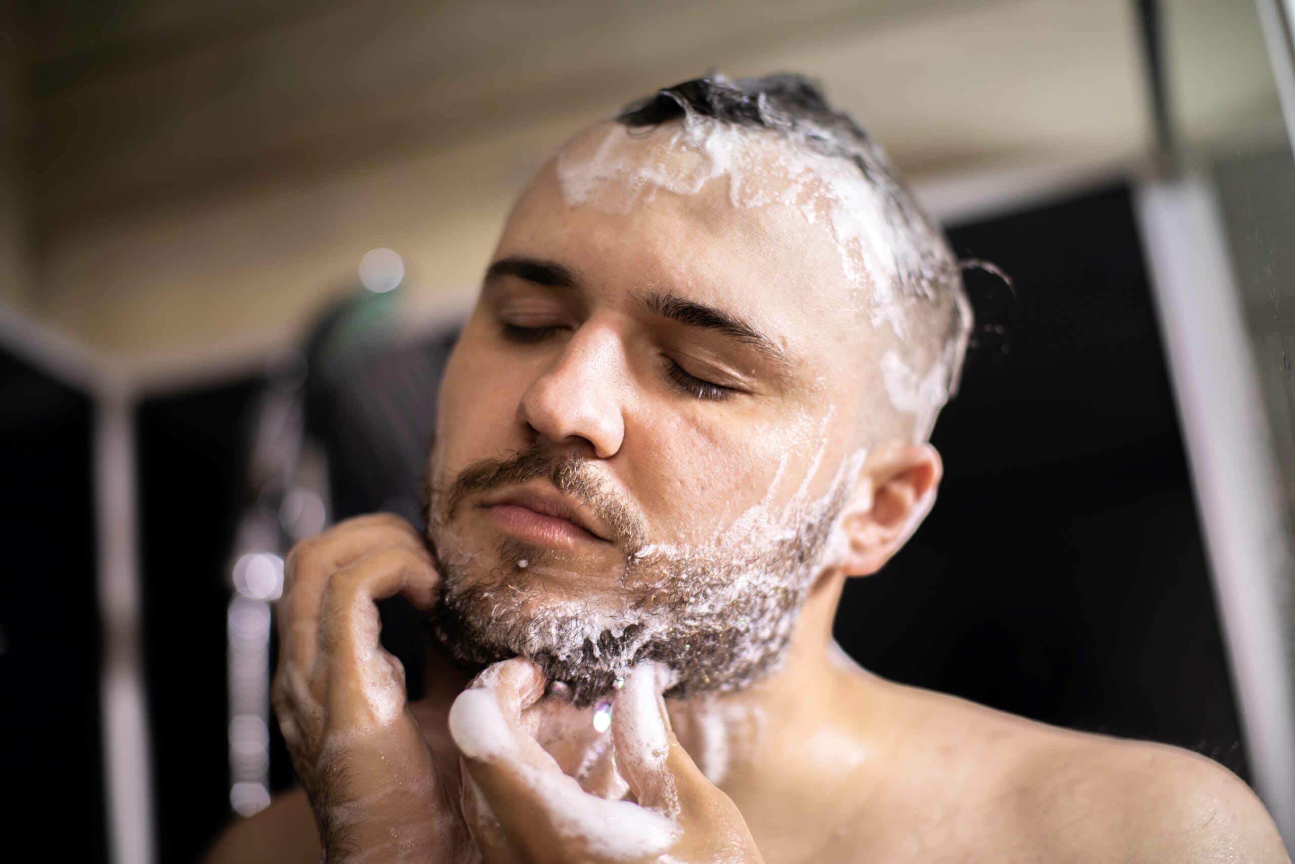 Homem lavando o rosto e esfregando a barba