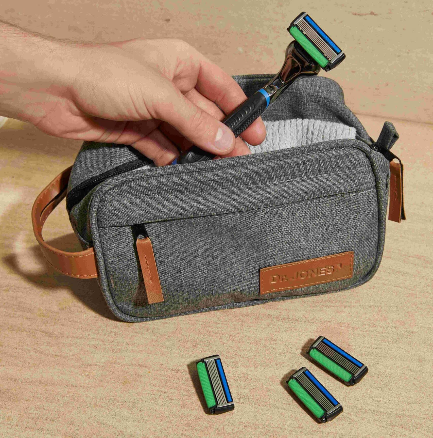 Bag com Barbeador The Razor em cima de uma mesa com três lâminas ao redor