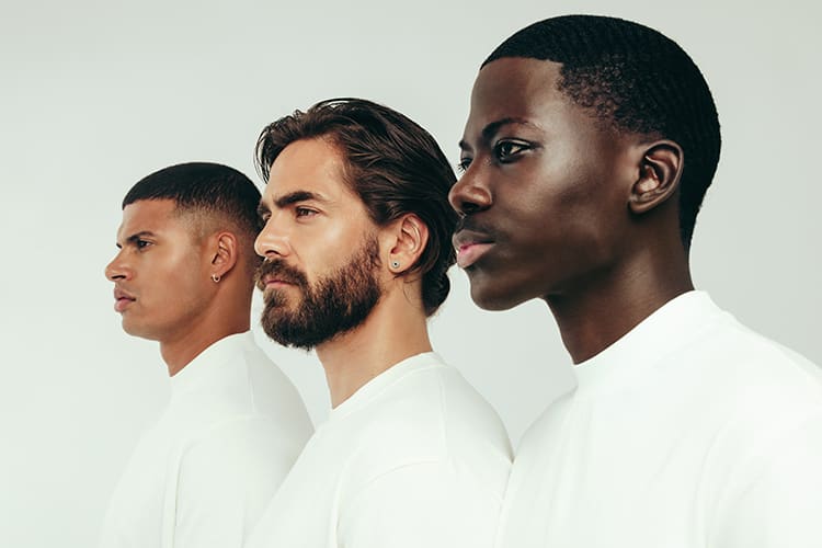 Em fundo branco, foto com 3 homens, de diferentes etnias: branco, negro, pardo, sobre os tipos de pele masculina.