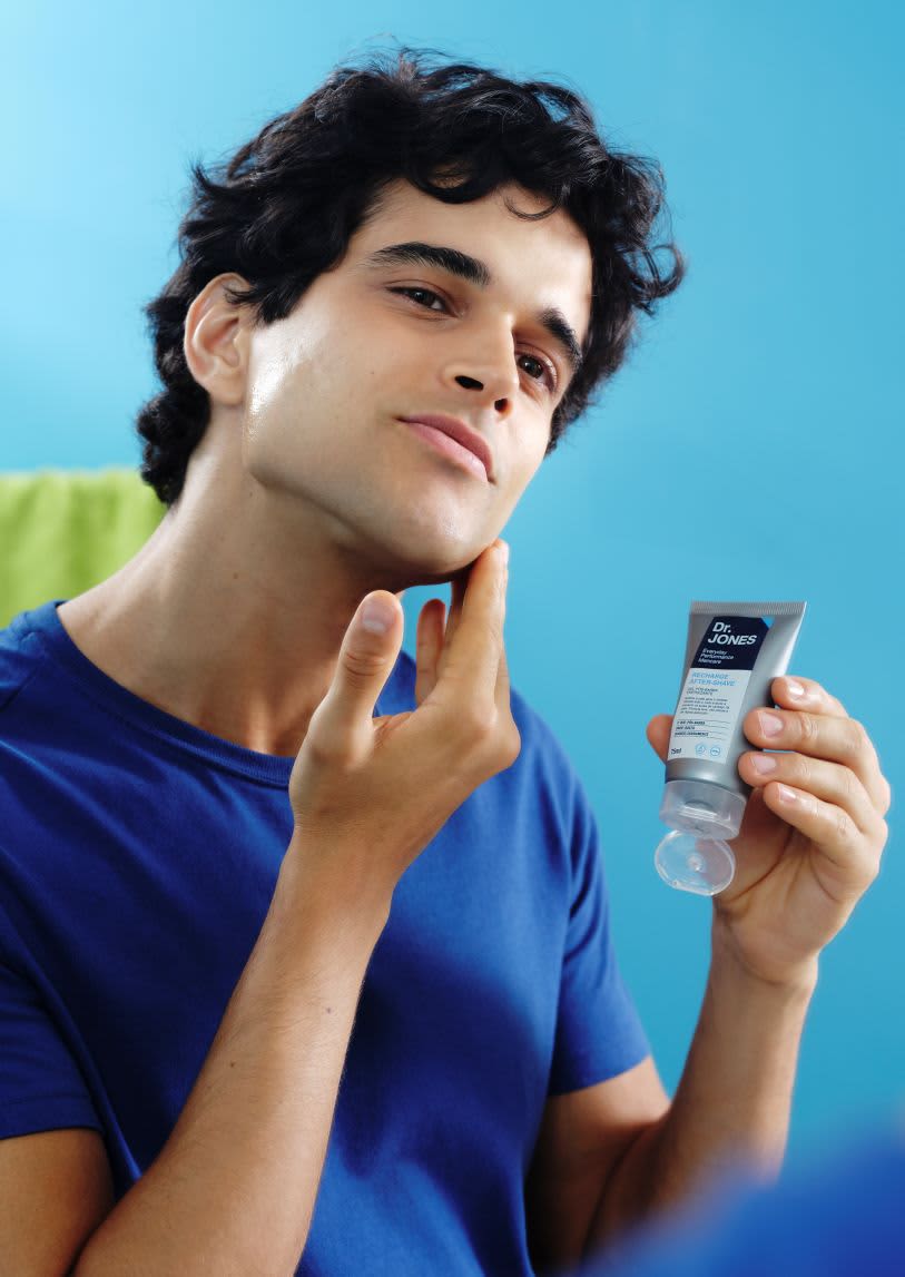 Homem aplicando produto de cuidados masculinos no rosto, segurando embalagem Dr. Jones.