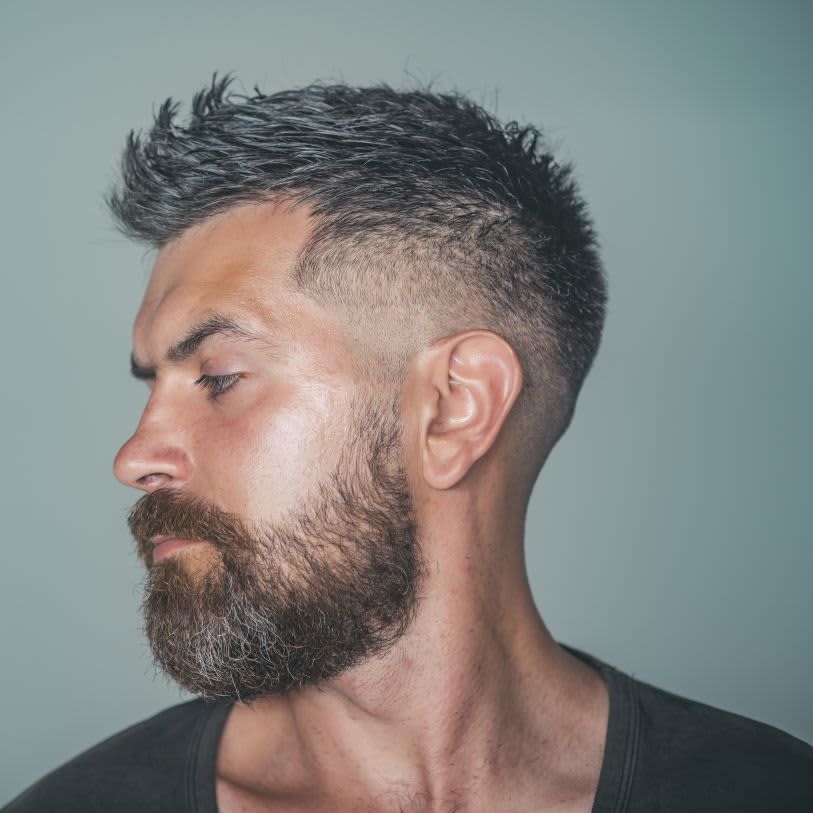 Homem com barba e cabelos grisalhos com corte degradê masculino