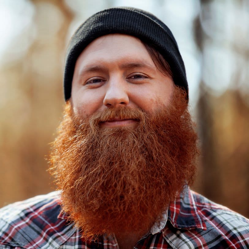 Homem usando uma toca preta, ele tem uma barba longa em tons de ruivo