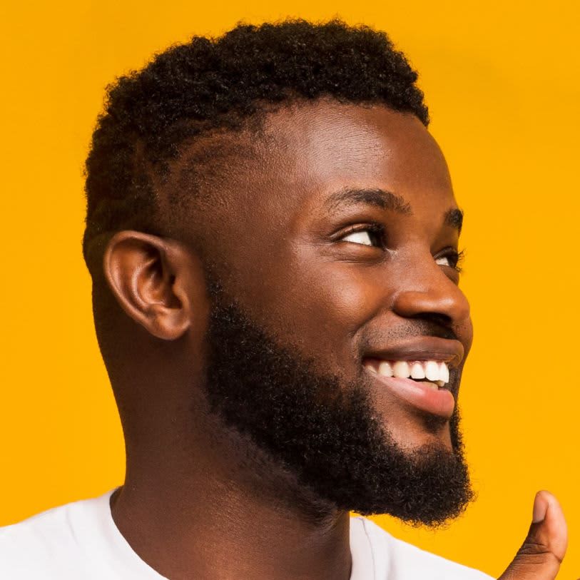 Homem negro de com um corte de cabelo curto e uma barba cheia.