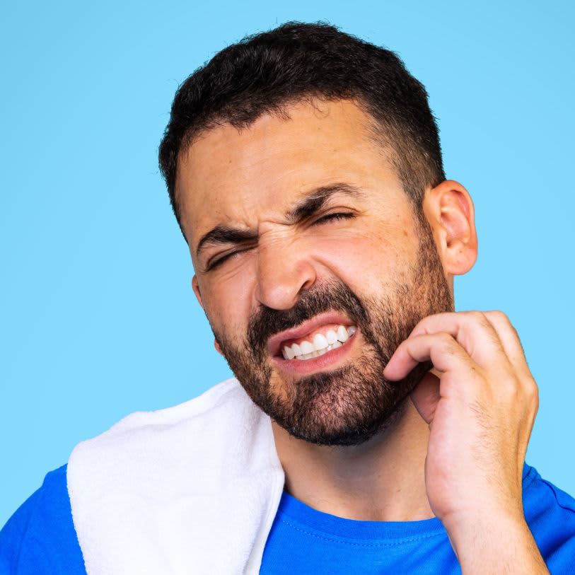 Homem coçando a barba com expressão de desconforto