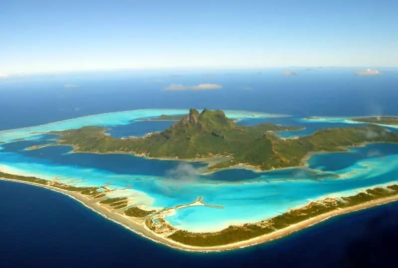 Foto aérea da Ilha de Bora Bora, destacando suas lagoas, montanhas e praias de areias brancas.