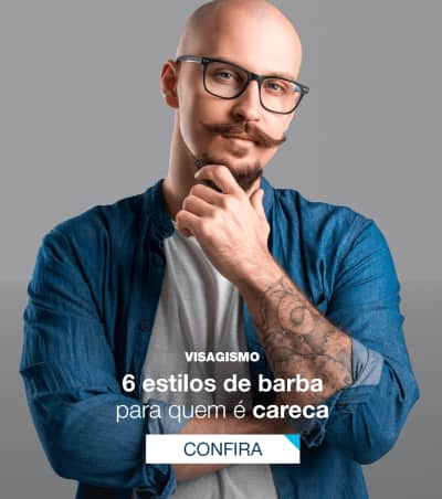 Homem careca, pele clara, de óculos e barba, olhando para a câmera com um sorriso discreto.