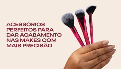 Uma mão segurando três pincéis de maquiagem de cor rosa. Acessórios perfeitos para dar acabamento nas makes com mais precisão.