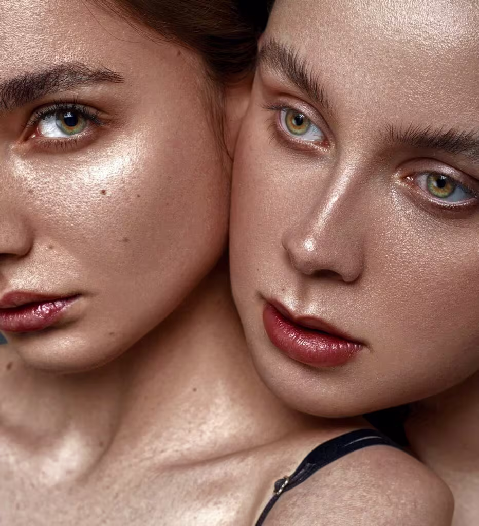 duas mulheres com foco no rosto, a pele bem iluminada com as sobrancelhas preenchidas. Na boca, a maquiagem de carnaval se destaca pelo gloss cor de boca.