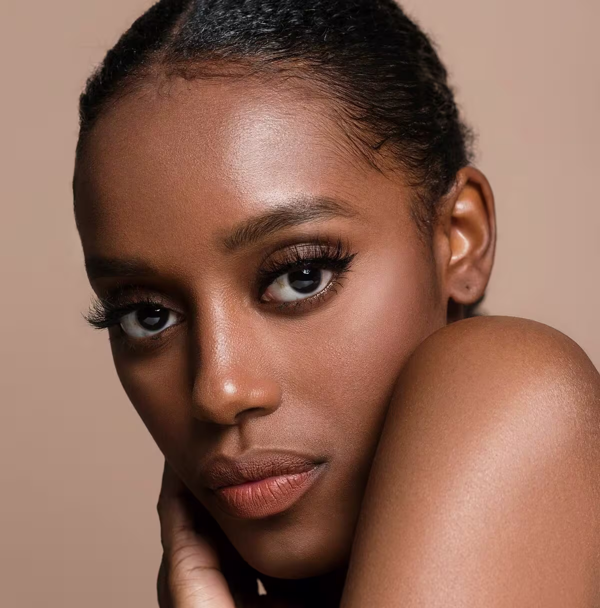 Mulher com sobrancelhas naturais e pele glow olhando para a câmera.