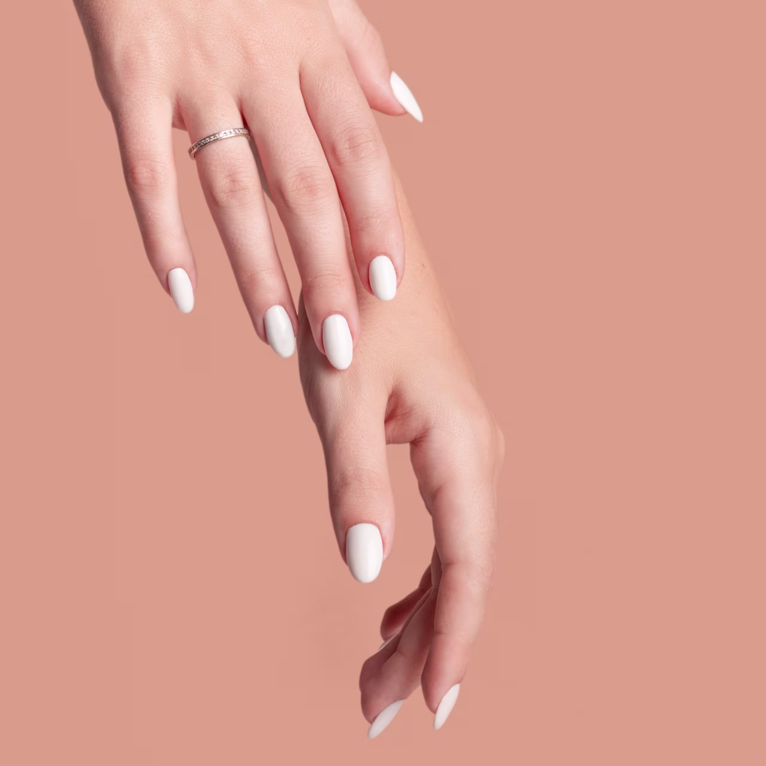 Mãos femininas com unhas curtas e arredondadas pintadas de branco.