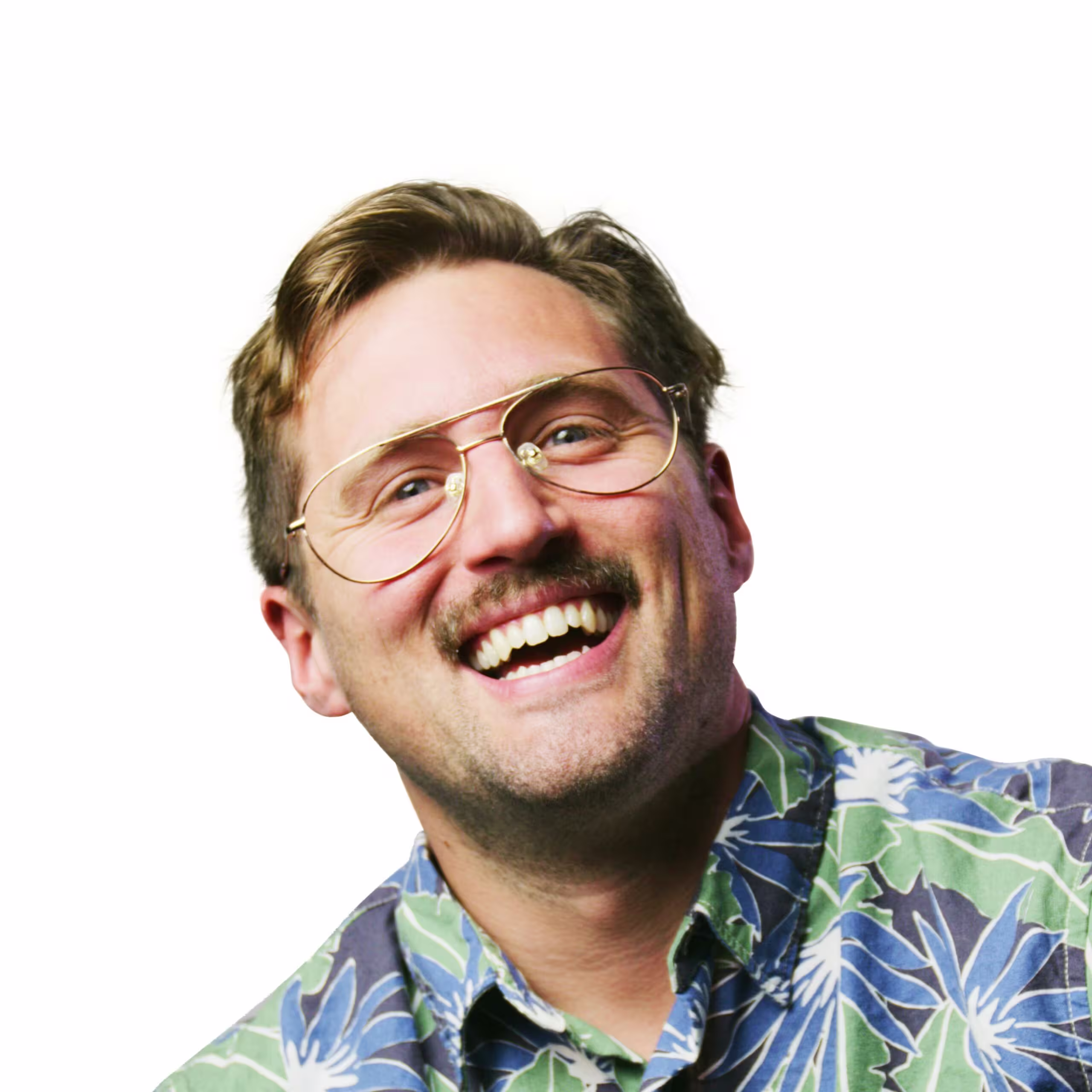 Homem sorrindo. Ele usa óculos, bigode e uma camisa estampada