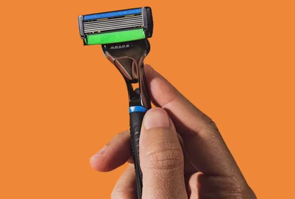 Em fundo laranja, foto de mão segurando o aparelho The Razor6, da Dr. JONES.
