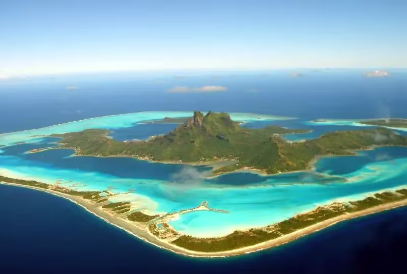 Foto aérea da Ilha de Bora Bora, destacando suas lagoas, montanhas e praias de areias brancas.