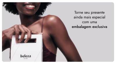 A imagem mostra uma pessoa sorridente com cabelos cacheados escuros, segurando uma embalagem branca com o texto "beleza na web". O texto na imagem diz "Torne seu presente ainda mais especial com uma embalagem exclusiva".