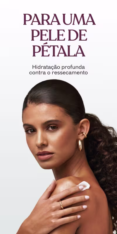 Mulher com cabelos presos atrás da orelha, aplicando creme corporal no ombro, comunicando hidratação profunda como o ressecamento.