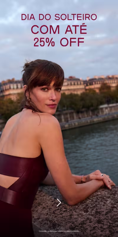 Mulher de cabelos presos, apoiada em uma mureta com o cenário de Paris de fundo, comunicando a promoção de Dia do Solteiro.