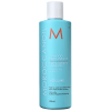A imagem mostra o Shampoo Moroccanoil Extra Volume 250ml. O frasco possui uma cor azul ciano vibrante, com letras em branco, preto e laranja. Também há informações de que é um produto para cabelos finos.