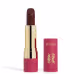 Embalagem de um batom aberto, com corpo dourado e tampa e base rosa, escrito "Eudora Niina Secrets". A cor do batom é marrom escuro e tem um relevo exclusivo em padrão floral na bala. Produto de beleza com design elegante e sofisticado.