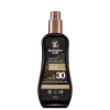 Embalagem âmbar com detalhes dourados, formato de frasco spray. Rótulo indica "Instant Bronzer", fator de proteção solar FPS 30, resistente à água e suor. Apresenta o logotipo da marca com um coala.