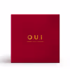 A imagem mostra uma caixa de embalagem quadrada na cor vermelha. No centro da caixa, está impresso o logotipo "O.U.i" em dourado. A cor vermelha vibrante e o acabamento de qualidade transmitem uma sensação de sofisticação e luxo.