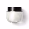 Frasco de vidro arredondado, transparente com tampa preta de rosquear, contendo o creme na cor branca. Design minimalista e elegante.
