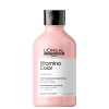 Frasco de plástico rosa com tampa preta. Rótulo com texto "L'OREAL PROFESSIONNEL PARIS Vitamino Color" e "SHAMPOOING PROFESSIONNEL". Produto de cuidados capilares para cabelos coloridos.