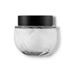 Frasco de vidro transparente arredondado com tampa preta. O recipiente tem uma forma esférica achatada. A tampa preta opaca contrasta com o vidro transparente do frasco que contém o creme na cor branca.