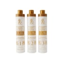 São três frascos de produtos para definir e tratar cabelos cacheados, da linha Defining Curl da marca Professional Paris Cosmetics. Os frascos cilíndricos têm tampa dourada e corpo branco com detalhes em dourado.