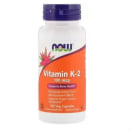 Este é um suplemento vitamínico da marca Now Foods, em um pote branco com tampa azul. O rótulo laranja destaca que é Vitamina K-2 na dosagem de 100 mcg. Menciona que suporta a saúde óssea e o metabolismo adequado do cálcio. O frasco contém 100 cápsulas