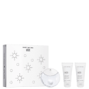 Caixa branca com padrão de bolinhas em tons de cinza. Contém um perfume em frasco redondo branco com tampa e dois tubos de creme para as mãos.