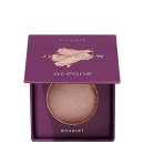 Iluminador em pó Just Glow da marca Océane. Embalagem compacta quadrada de cor roxa com o logotipo da marca e o nome do produto em letras douradas.