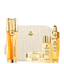 Conjunto de itens de perfumaria da marca Guerlain, incluindo frascos dourados, caixa bege com textura, e rótulos com o nome da marca e da linha "Abeille Royale". Os produtos parecem ser soros, loções e cremes para cuidados com a pele.