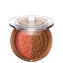 Pó bronzeador compacto em embalagem redonda de plástico transparente, com detalhes dourados e um desenho de sol estampado no centro. O produto possui uma tonalidade dourada brilhante.
